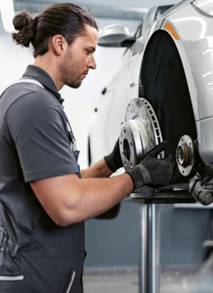 BMW Service Technician performing a brake disc change for a BMW vehicle on a lift in a BMW Service Center.