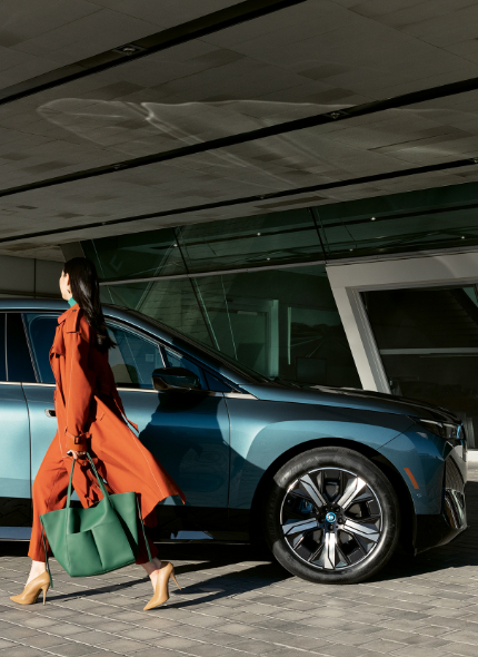 A customer stands next to a BMW vehicle parked outside a BMW Service Center.