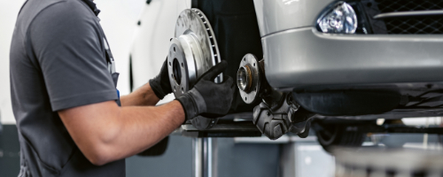 BMW Service Technician performing a brake disc change on a BMW vehicle on a lift in a BMW Service Center.